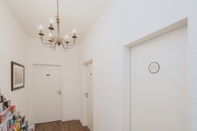 Doppelzimmer Fleetblick: Weißer Flur mit Kronleuchter, mehreren Türen, Türschild und Prospektständer