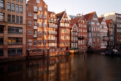 Doppelzimmer Fleetblick: Reihe historischer Backsteinhäuser mit Giebeln und Fachwerk am Wasser, Spiegelungen im Abendlicht