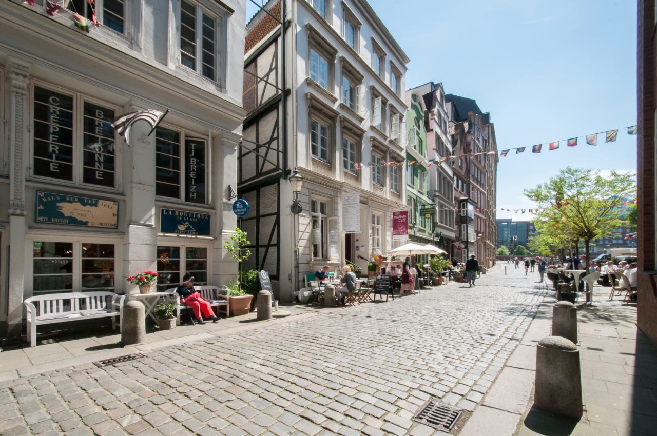 Doppelzimmer Fleetblick: Kopfsteingepflasterte Gasse mit historischen Giebelhäusern, Cafétischen unter Sonnenschirmen und Wimpelketten