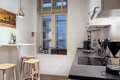 Habitación doble Fleetblick: Cocina con placa vitrocerámica, fregadero y campana extractora, mesa alta con taburetes de madera y ventana con travesaños