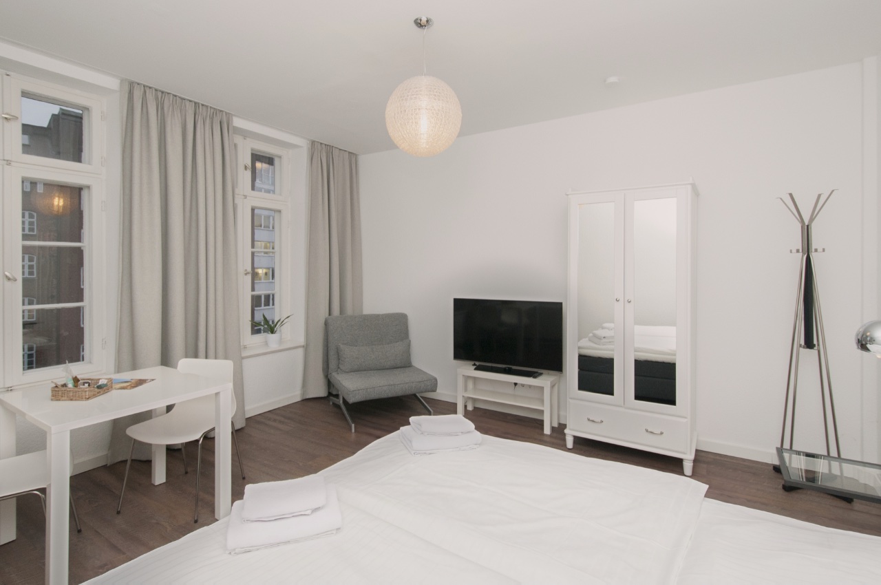 Habitación doble Fleetblick: Habitación clara con cama doble, televisor, armario blanco, sillón, mesa y ventanas con cortinas